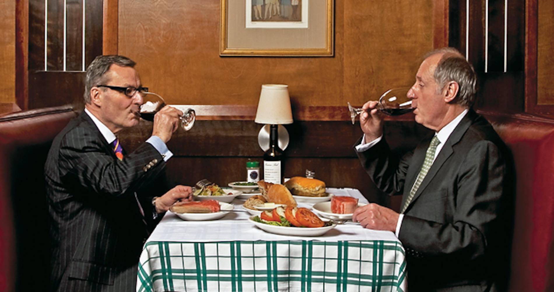 Photo of owners at a table drinking wine and with a full set table